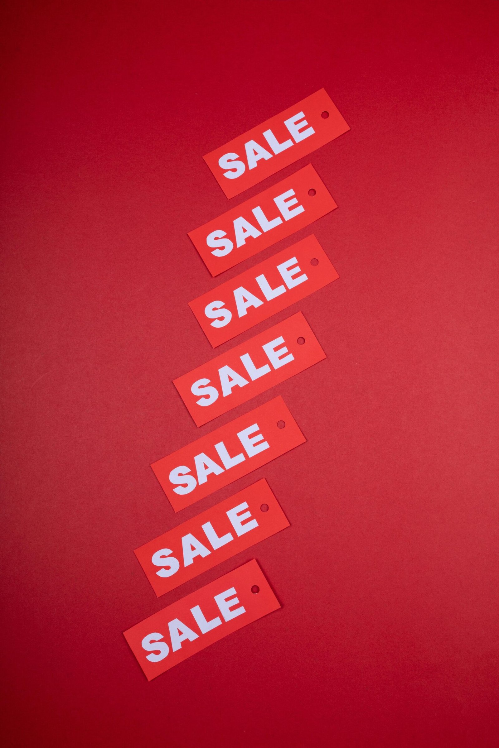 Vertical arrangement of red sale tags on a vivid red background, ideal for retail promotions.
